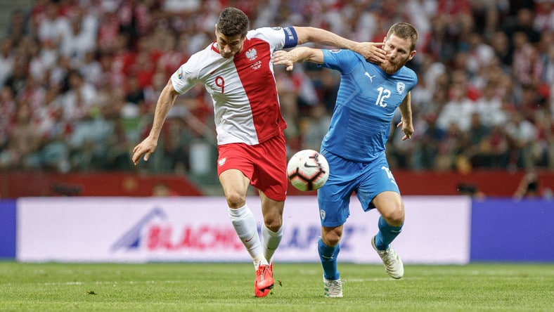 Zdjęcie pokazuje piłkarzy Polski i Izraela walczących o piłkę.